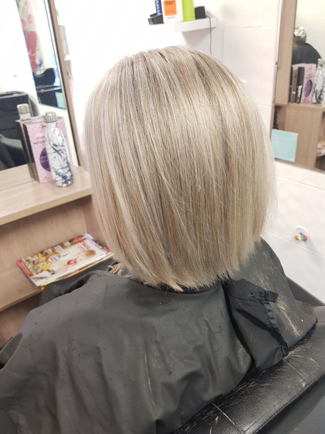 A woman with blonde bob hair sitting in a chair.
