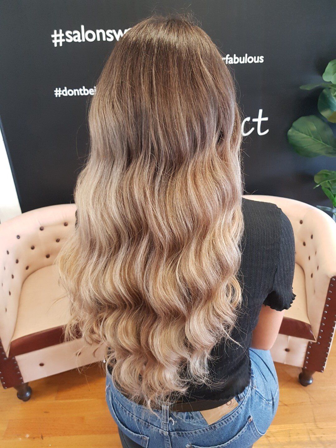 Back view of tightly curled hair with balayage effect.
