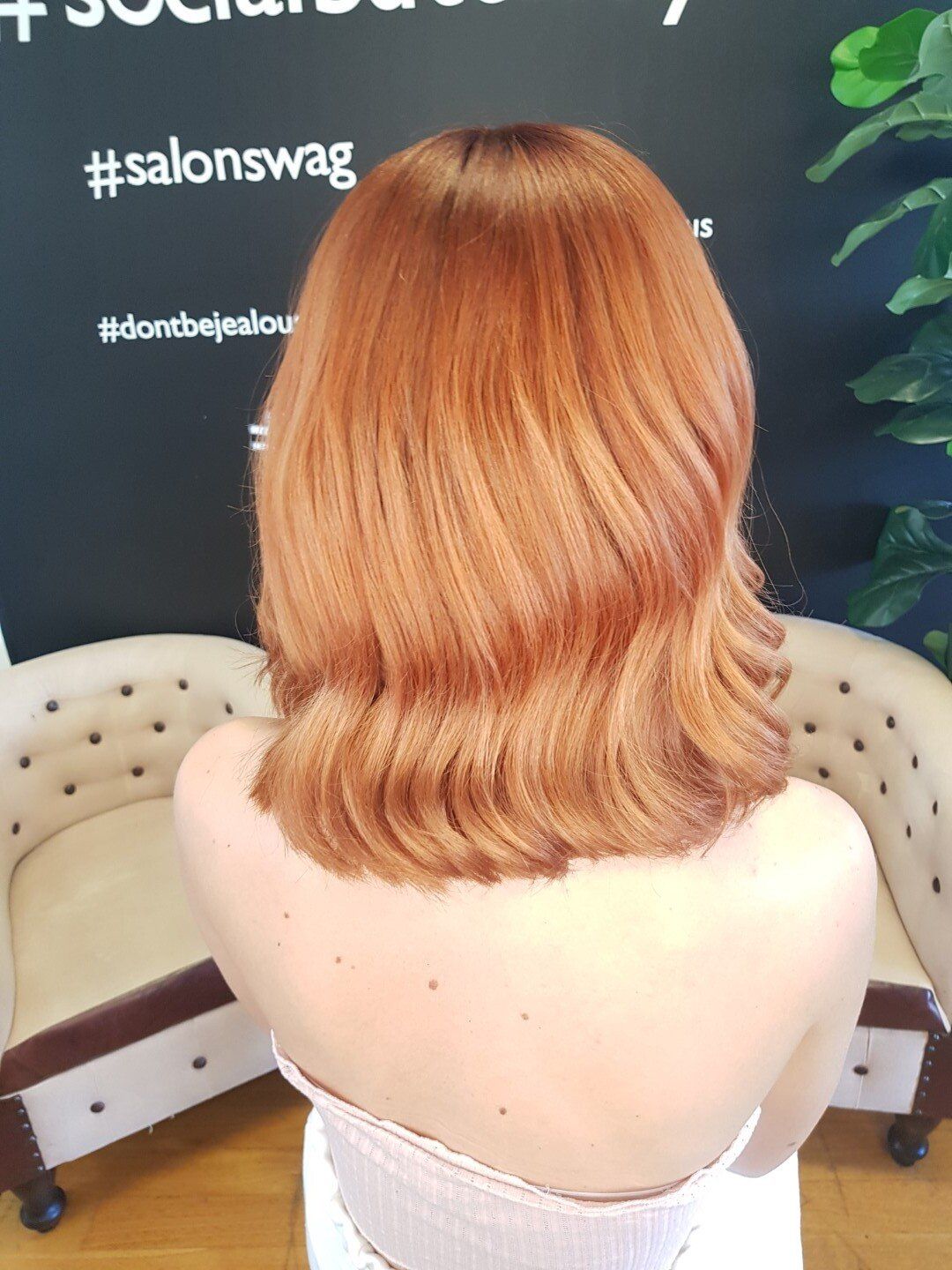 Rear view of vibrant orange hair with dark roots.
