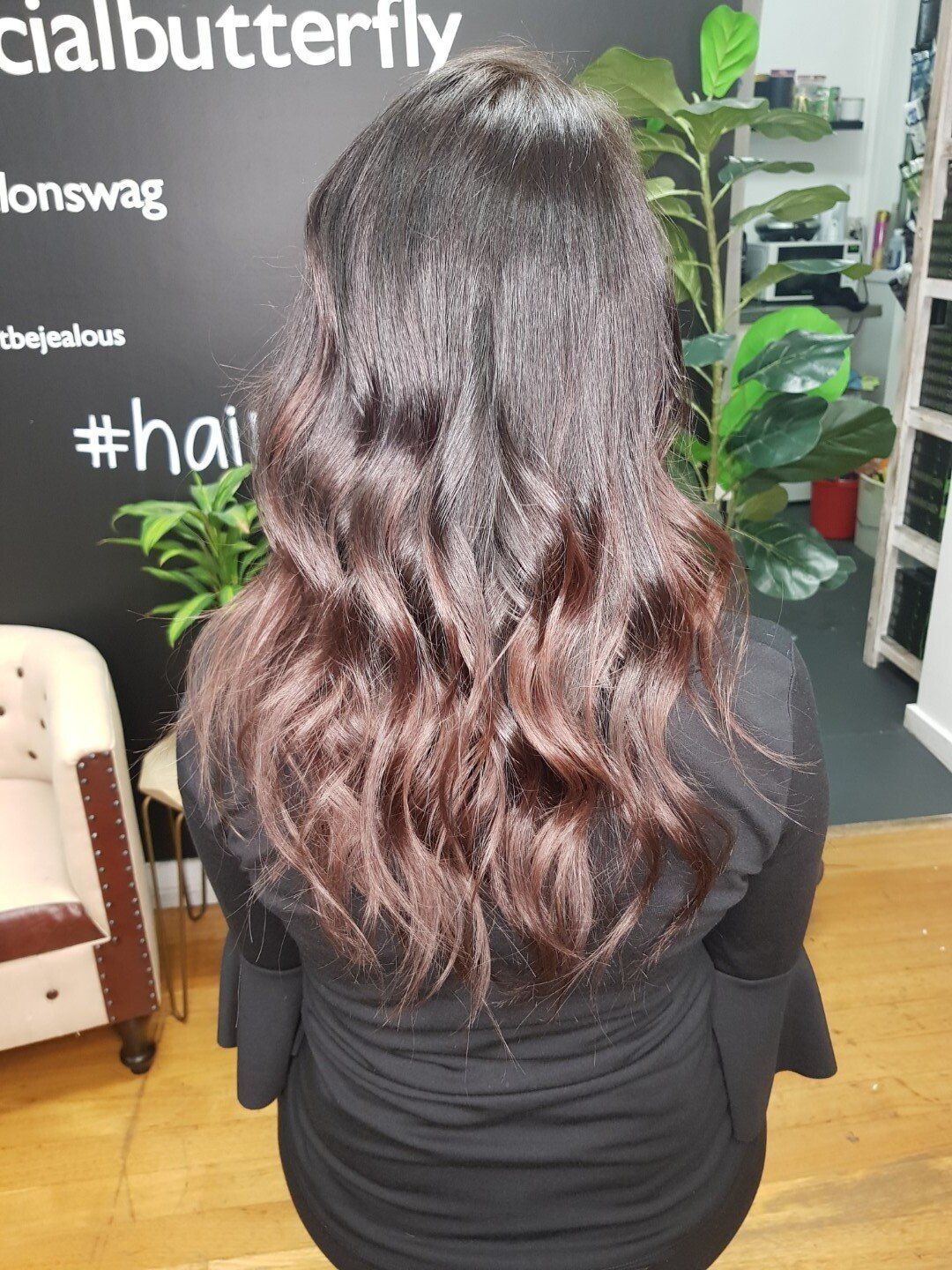 A woman with long wavy hair getting pampered at a salon.
