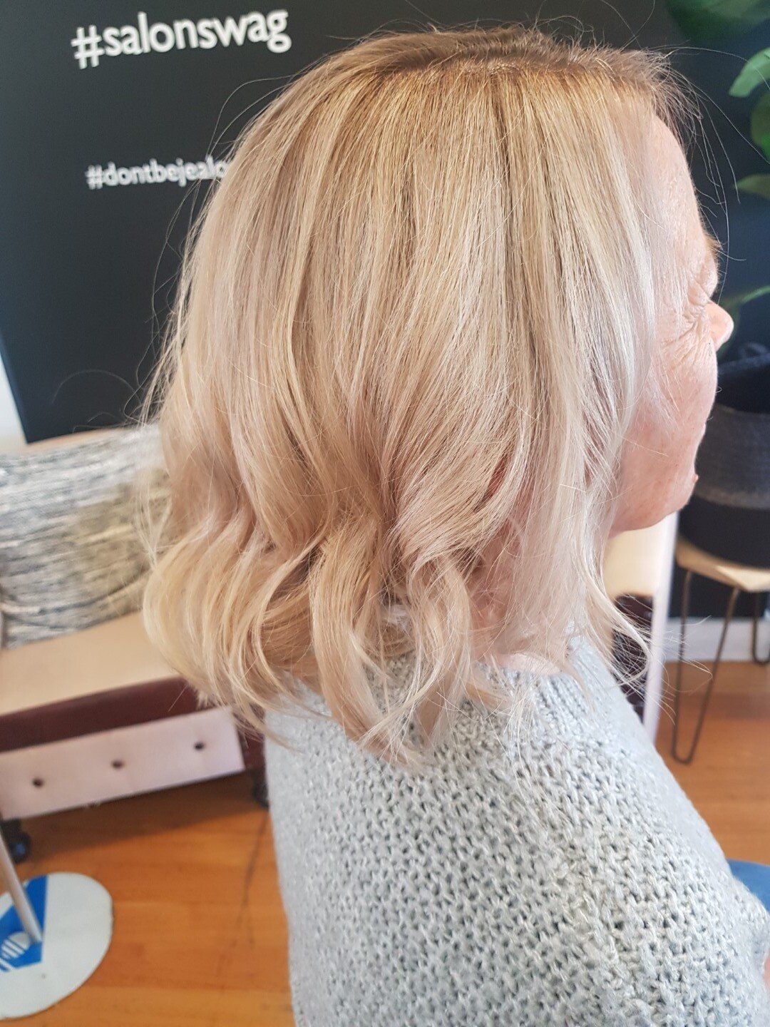 Woman with blonde hair sitting in a salon chair.
