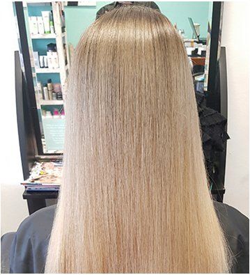 A woman with long hair is sitting in a chair in a salon.