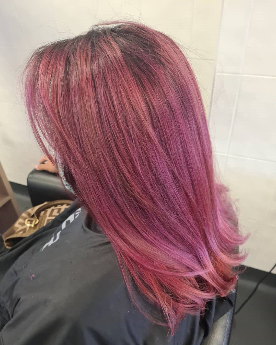 A back view of straight, shoulder-length, vibrant pink hair.
