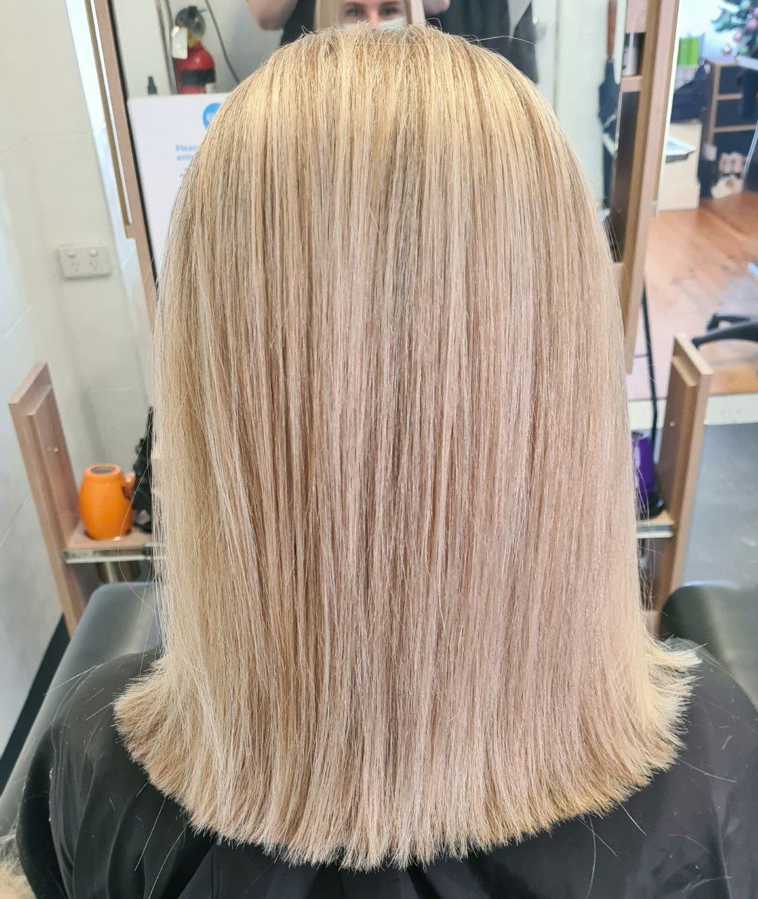 A back view of straight, medium-length blonde hair.
