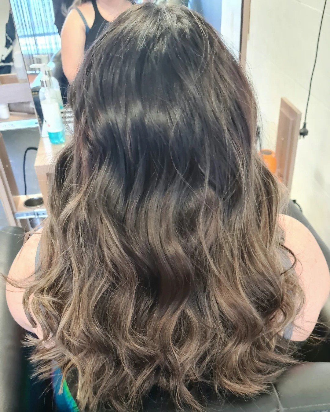 A back view of long, wavy, dark brown hair with subtle highlights.