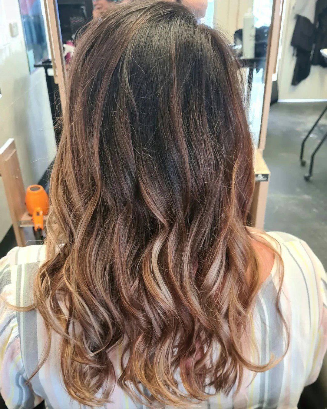 A back view of medium-length, wavy, brunette balayage hair