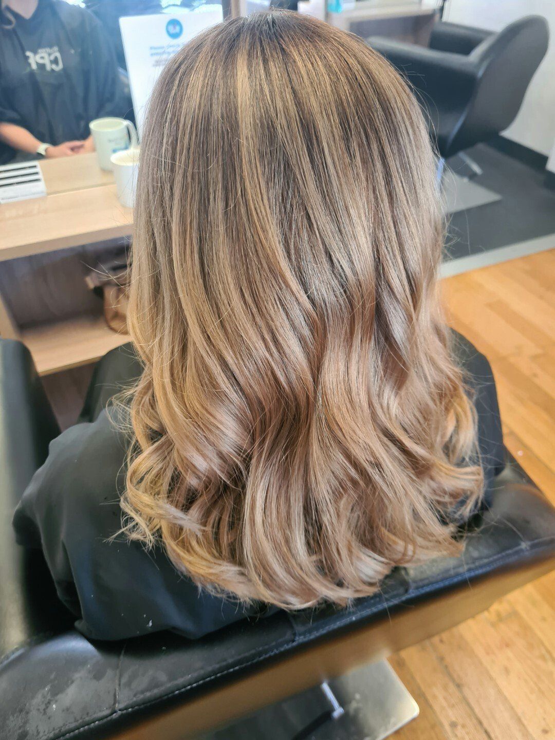 A woman with beautifully styled blonde hair sits in a salon chair
