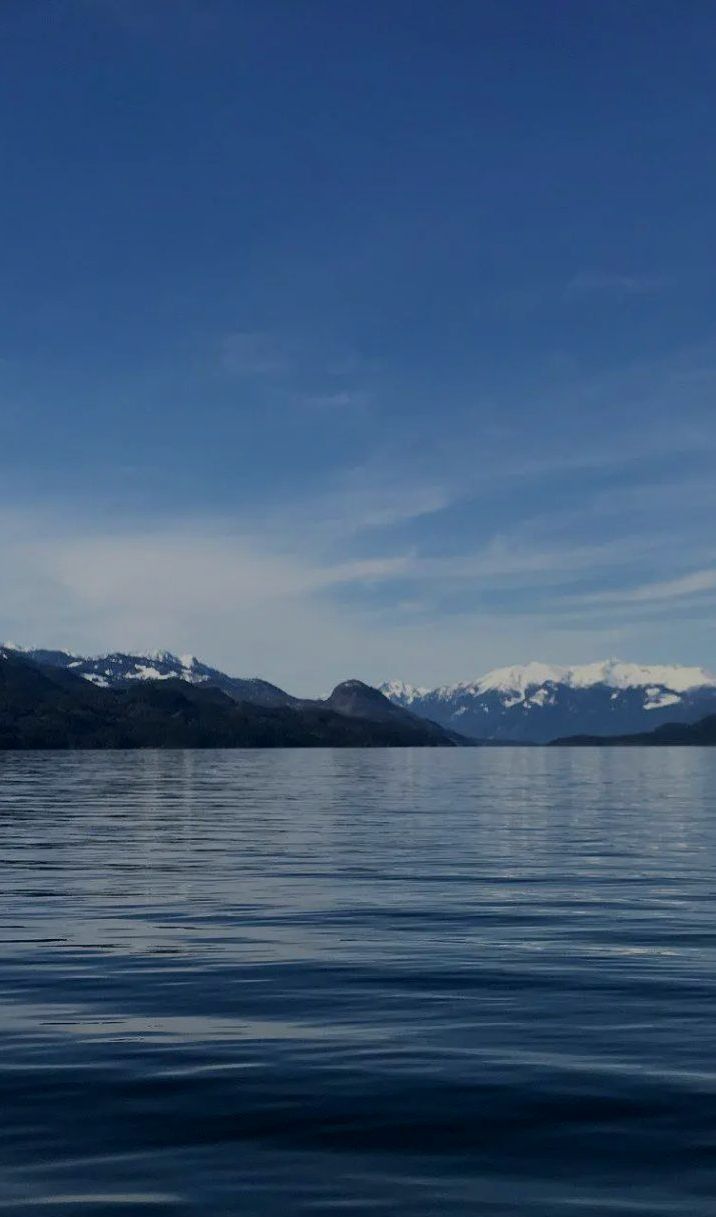 A lake with mountains in the background and a blue sky