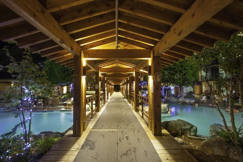 A long wooden walkway leading to a pool at night