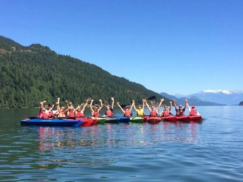 A group of people are rowing kayaks on a lake.