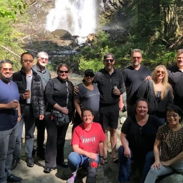 A group of people posing for a picture in front of a waterfall