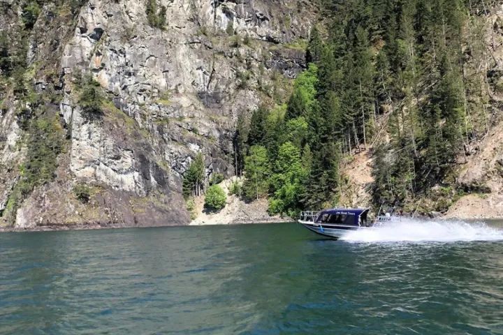 A boat is floating on a lake with a mountain in the background.