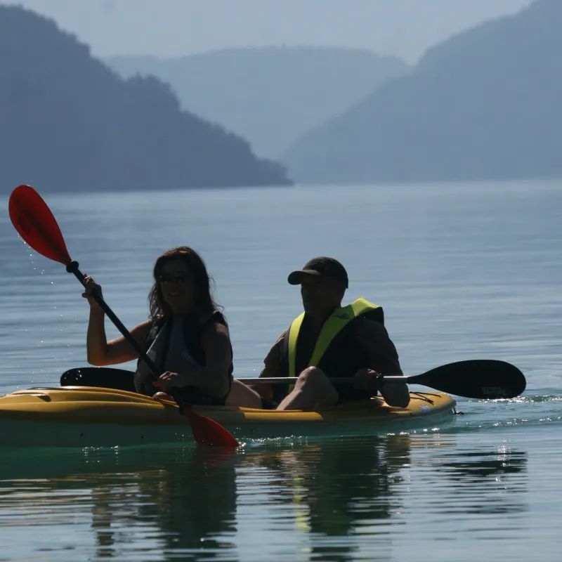 A man and a woman are paddling kayaks in the water