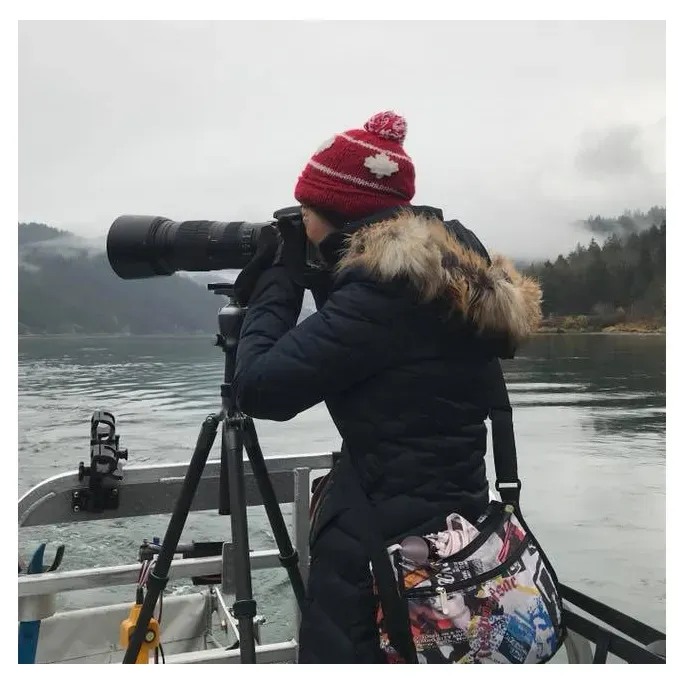 A woman taking a picture with a camera on a boat