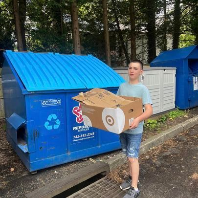 man throwing box in dumpster