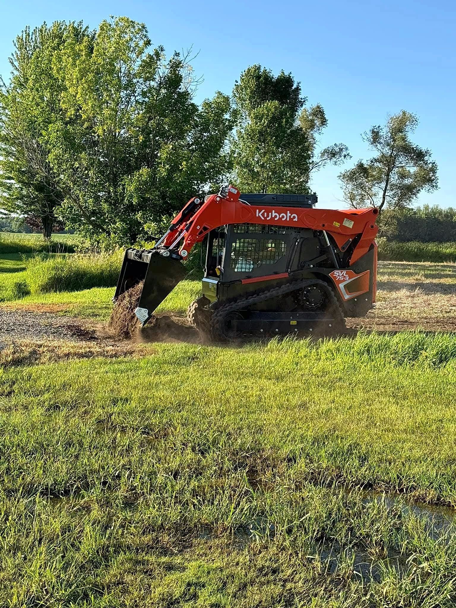 A bulldozer is digging a hole in a grassy field.