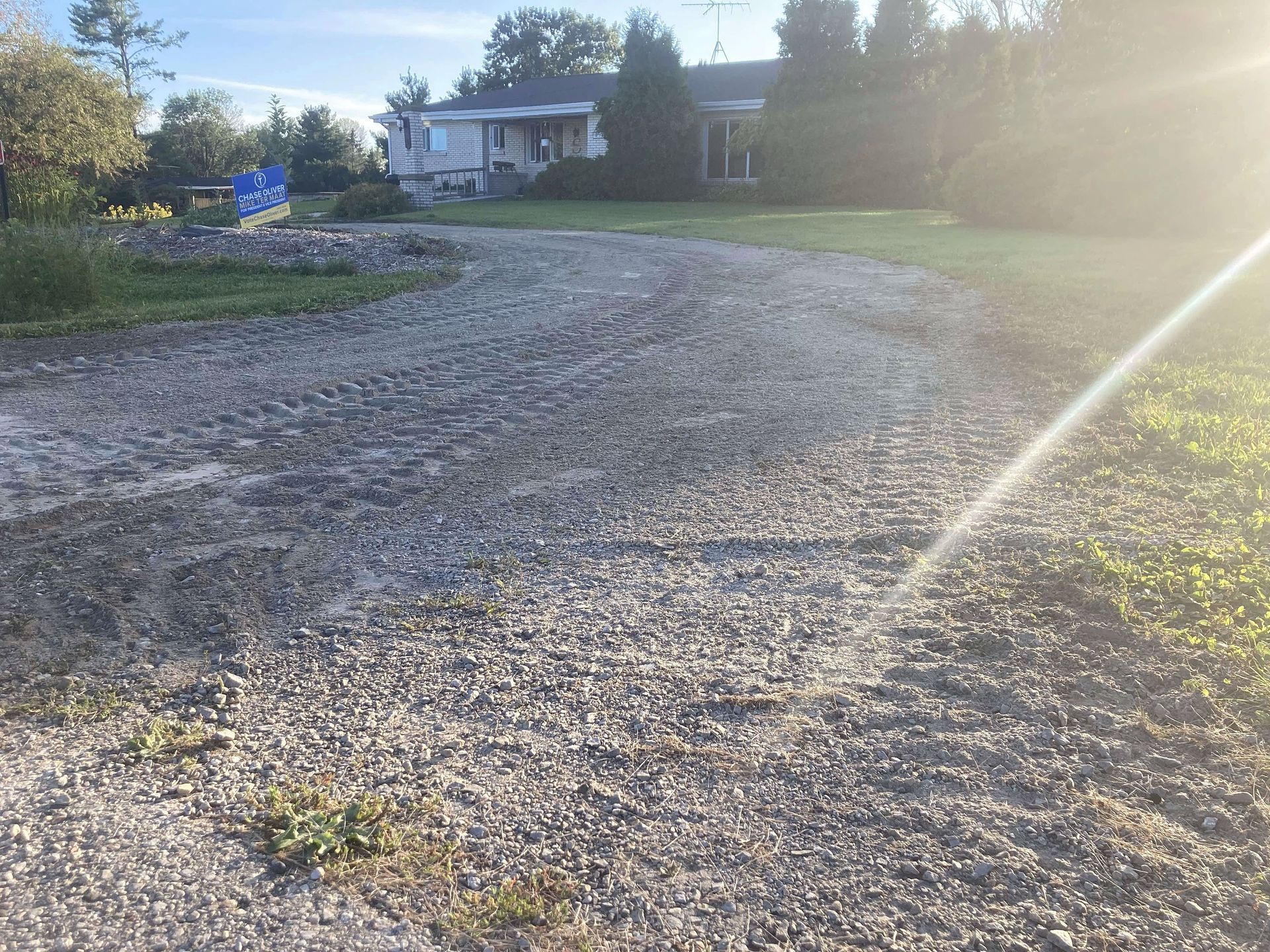 A gravel driveway with a house in the background.