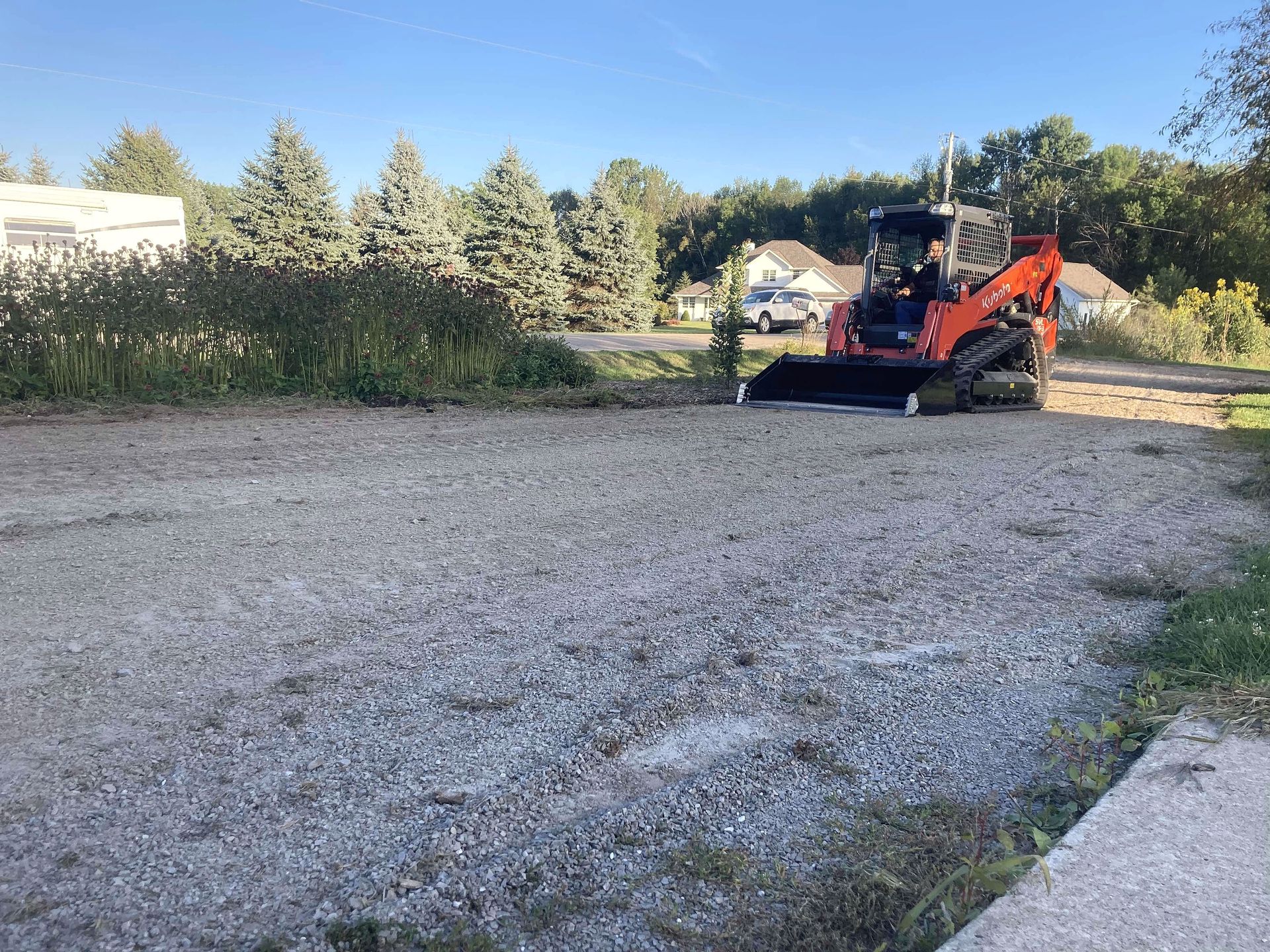 A bulldozer is parked in a gravel lot next to a sidewalk.