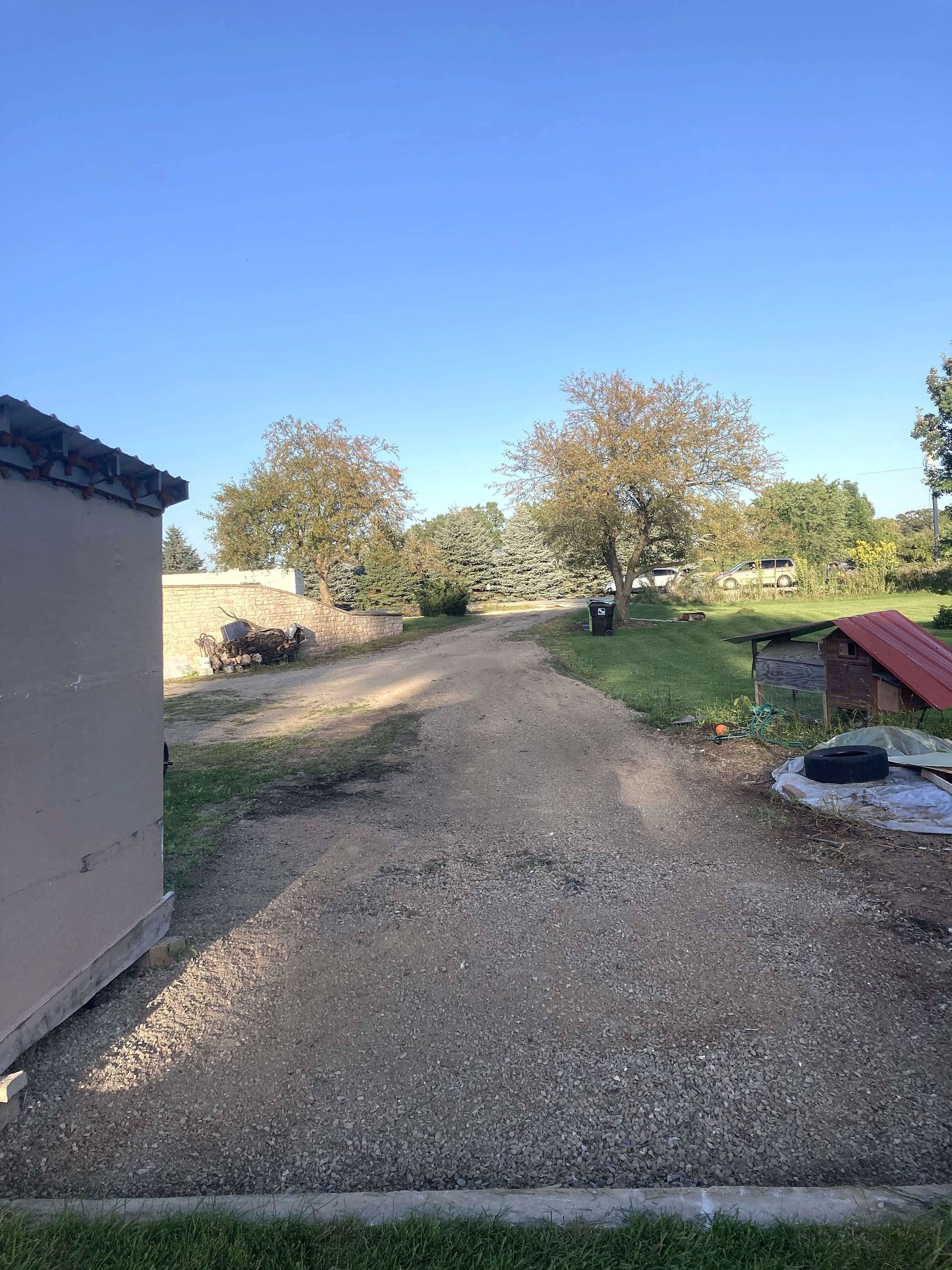 A dirt road leading to a shed and a chicken coop.