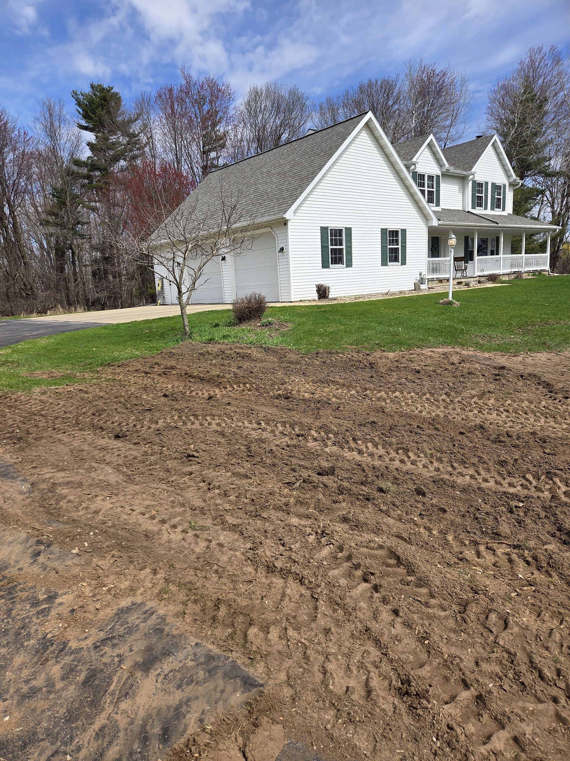 A white house is sitting on top of a hill next to a dirt field.
