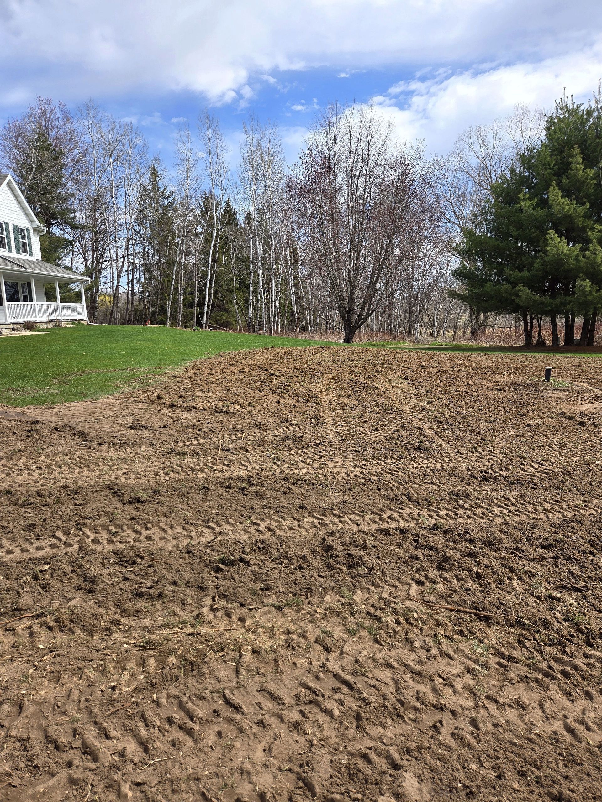 A large dirt field with a house in the background.