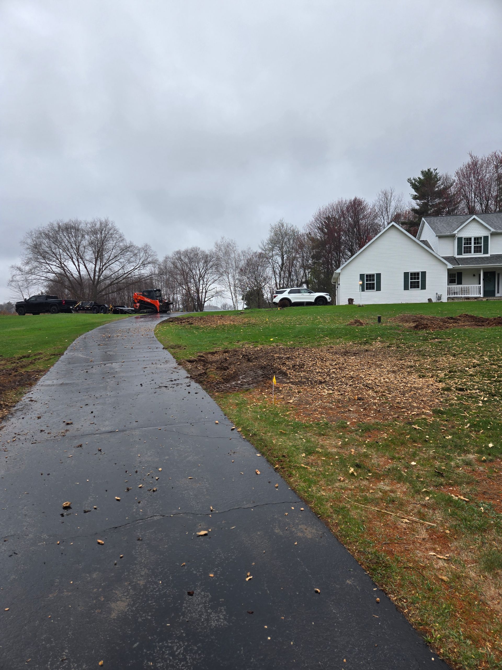 A driveway leading to a white house on a cloudy day.
