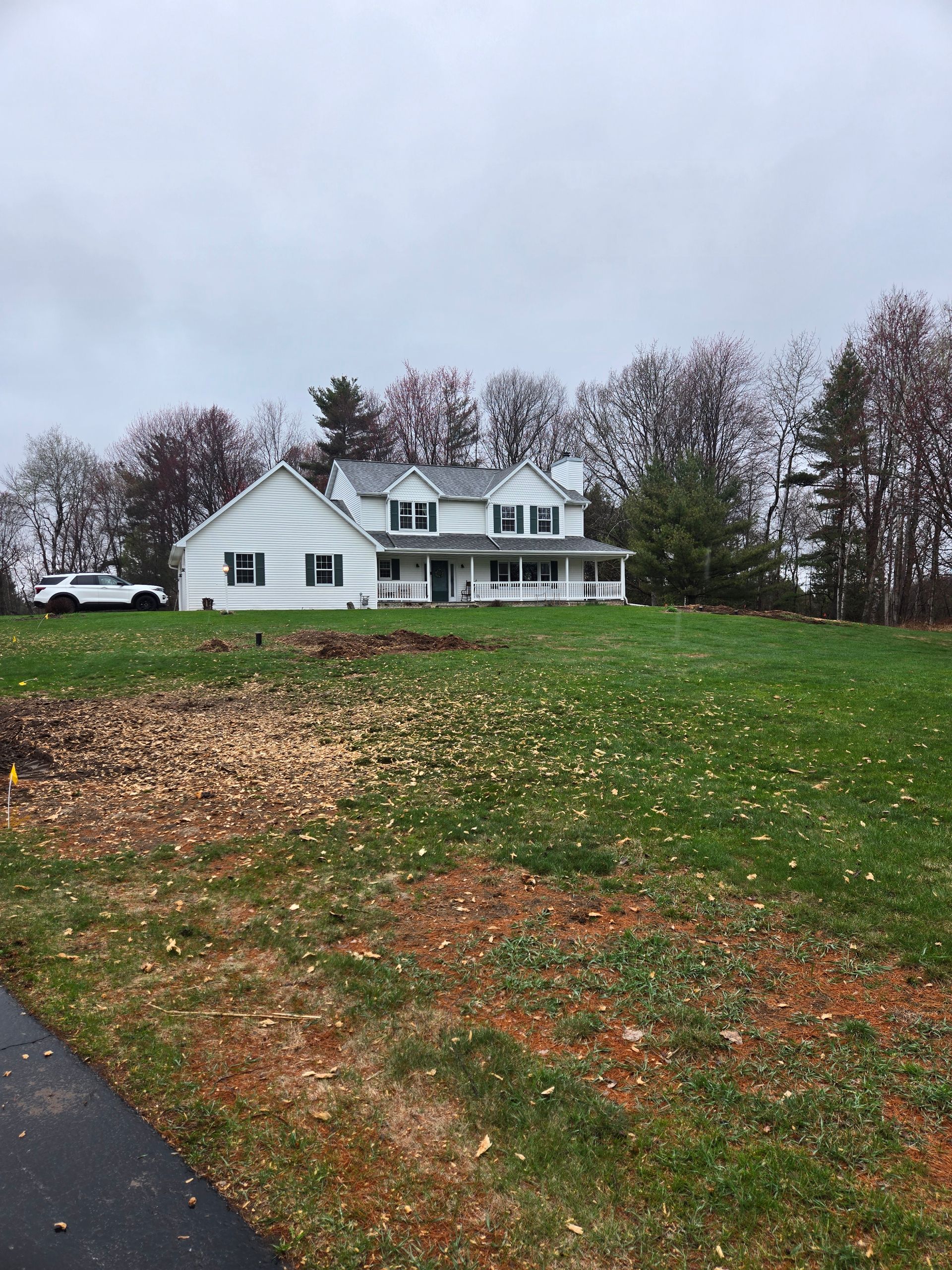 A large white house is sitting on top of a lush green field.