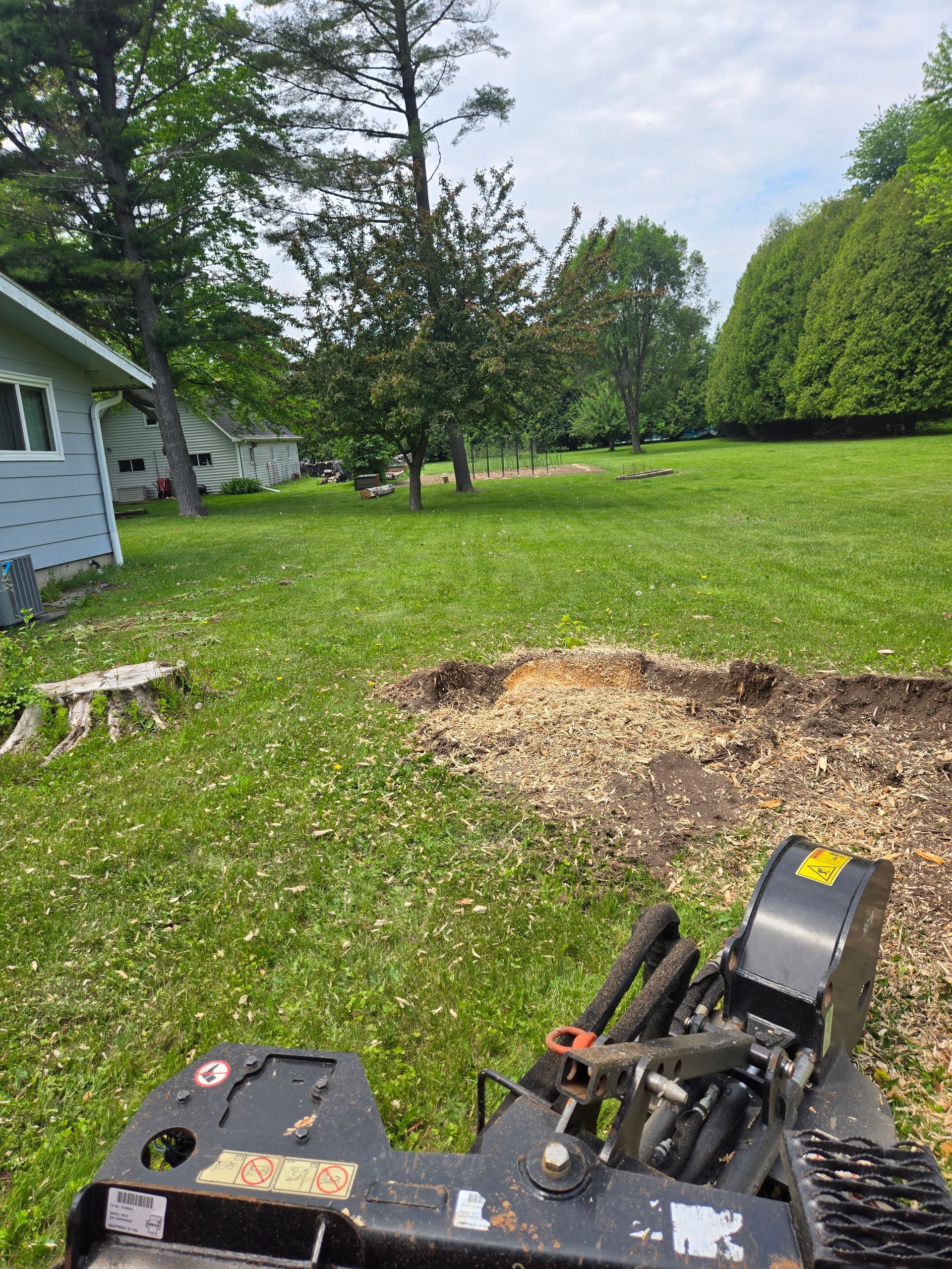 A stump grinder is sitting in the middle of a lush green field.