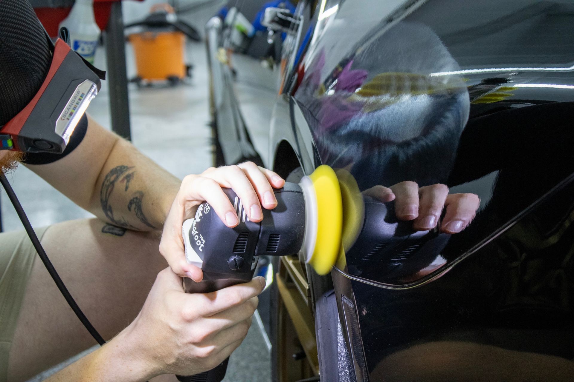 A person is polishing a car with a machine.