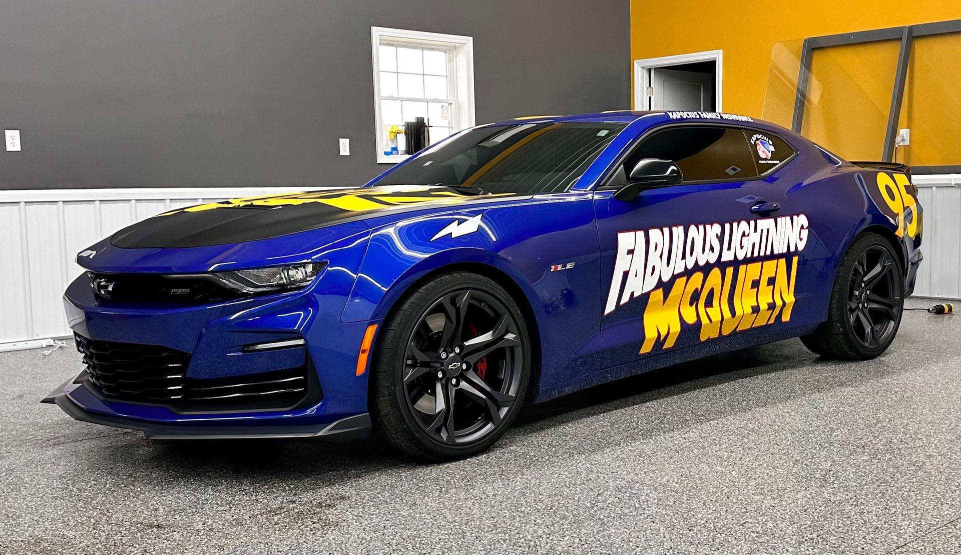 A blue chevrolet camaro is parked in a garage.