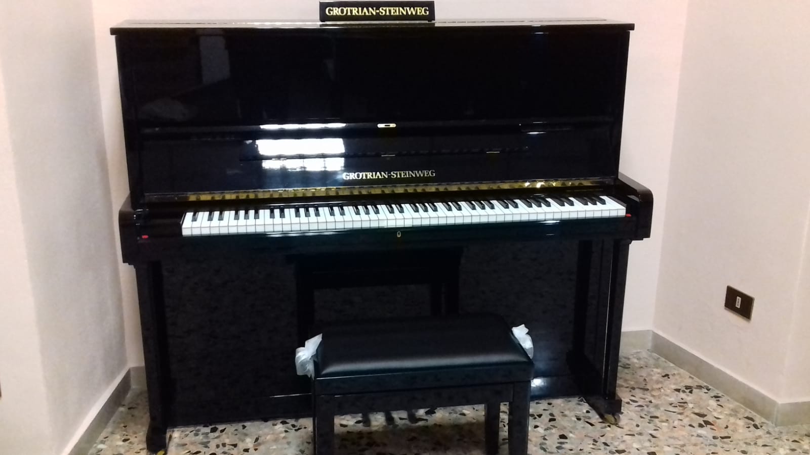Un pianoforte nero è appoggiato in un angolo di una stanza