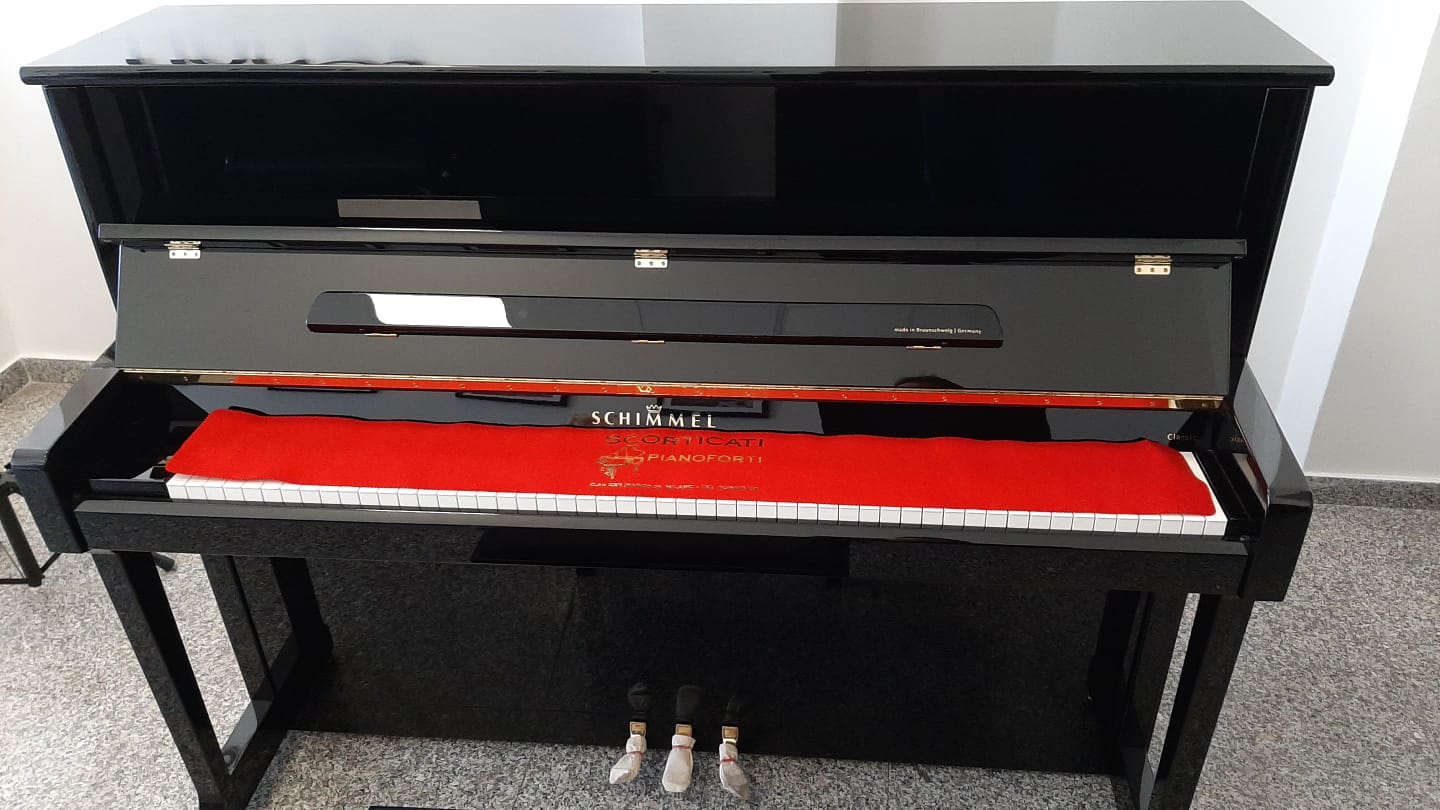 Un pianoforte nero con un cuscino rosso sui tasti