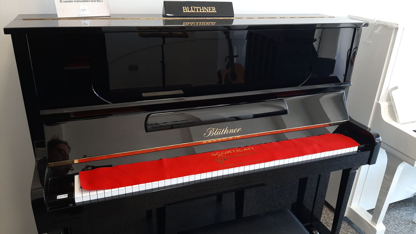 Un pianoforte nero con un cuscino rosso sui tasti