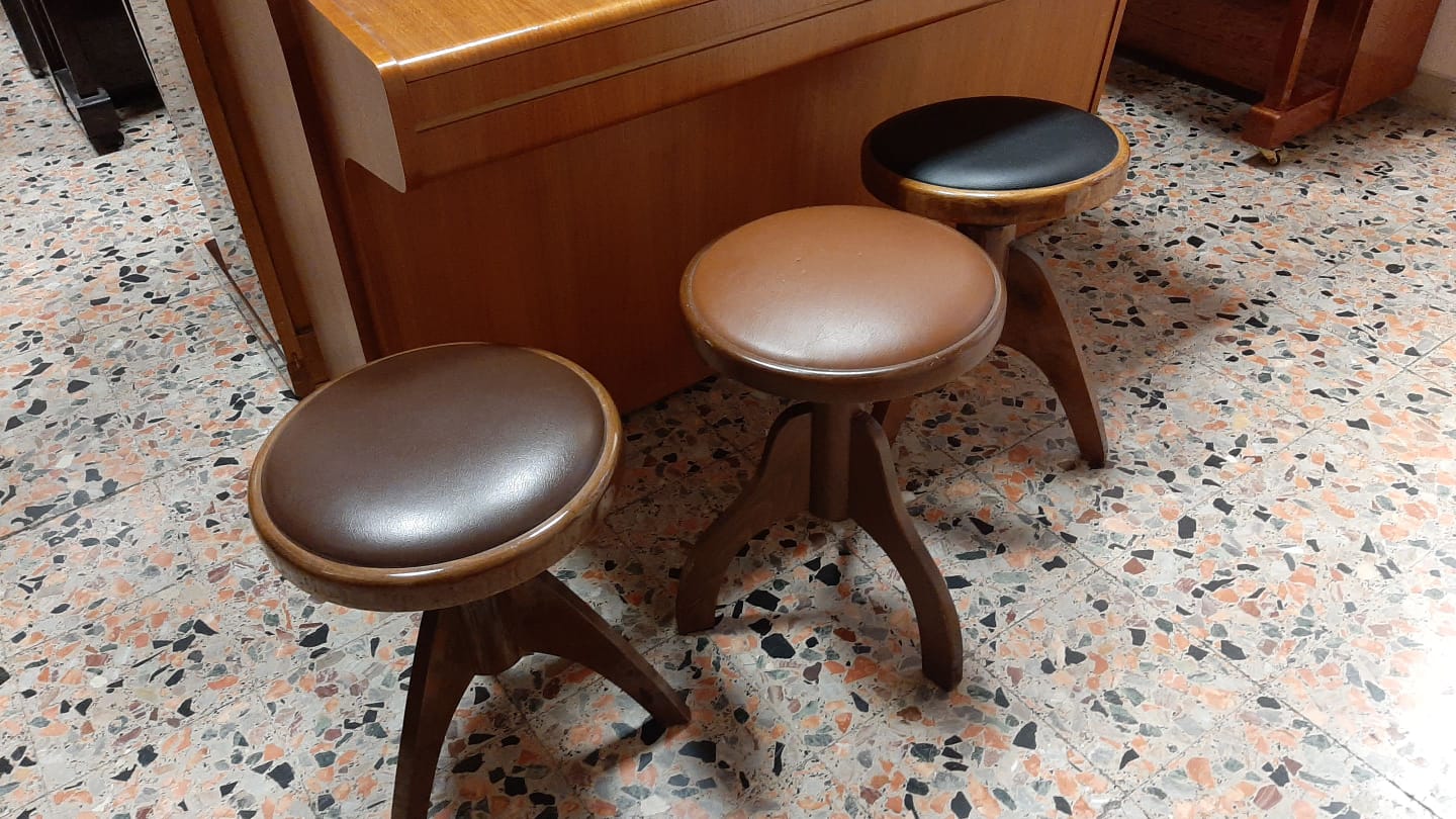 Due sgabelli marroni sono seduti davanti a un pianoforte