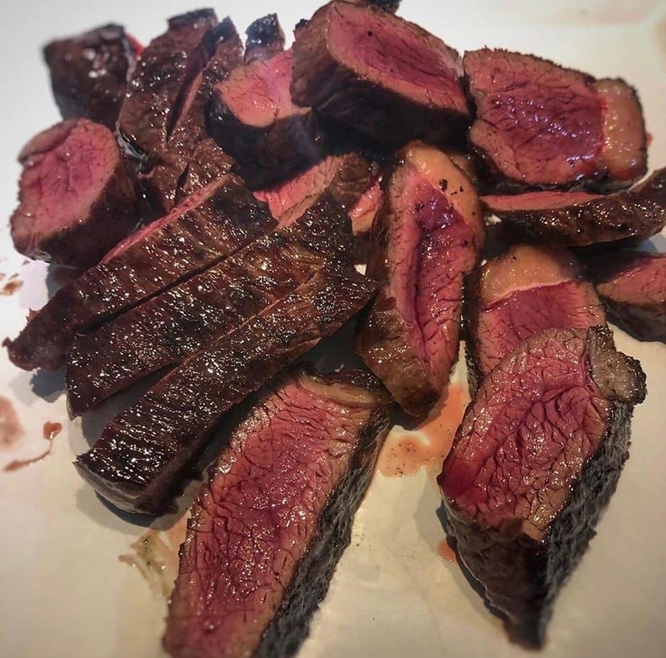 Bistecca tagliata, cotta al sangue, disposta su un piatto bianco. L'interno è rosa, l'esterno è dorato.