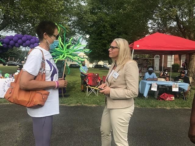 Two women are talking to each other in front of a red tent at a LCRC community event.