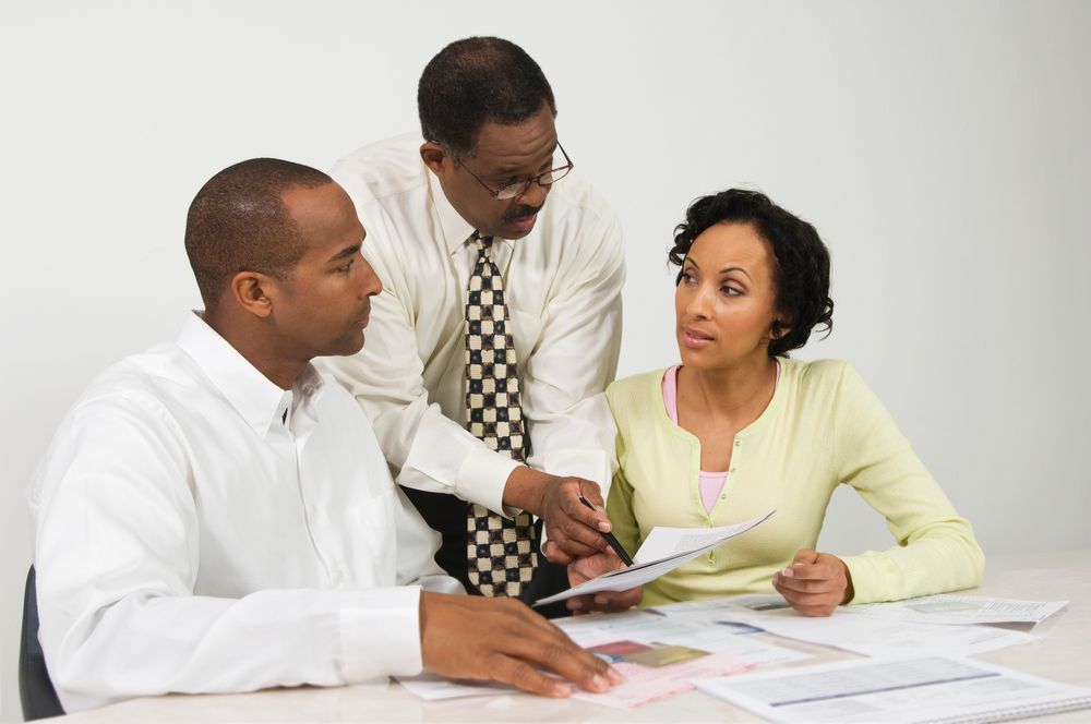 A group of people are sitting at a table looking at papers.