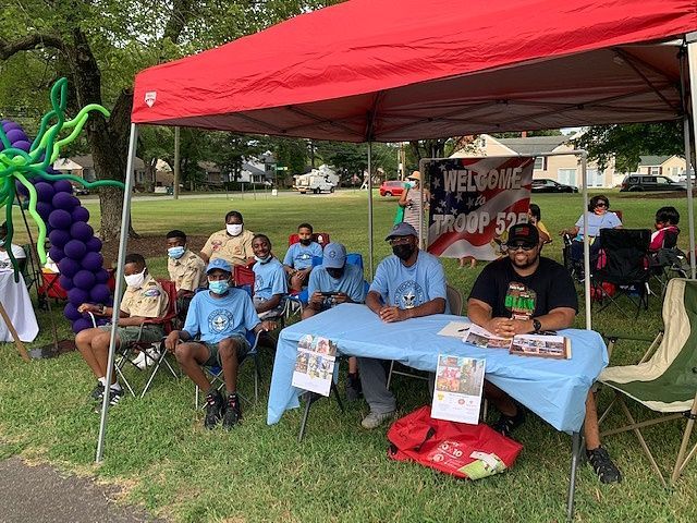 A group of people are sitting under a tent in a park at a LCRC community event.