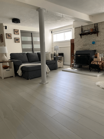 Salon avec canapé gris, cheminée et parquet en bois clair.