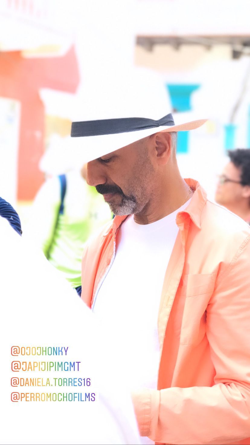 Un hombre que lleva un sombrero y una chaqueta rosa está de pie entre una multitud.