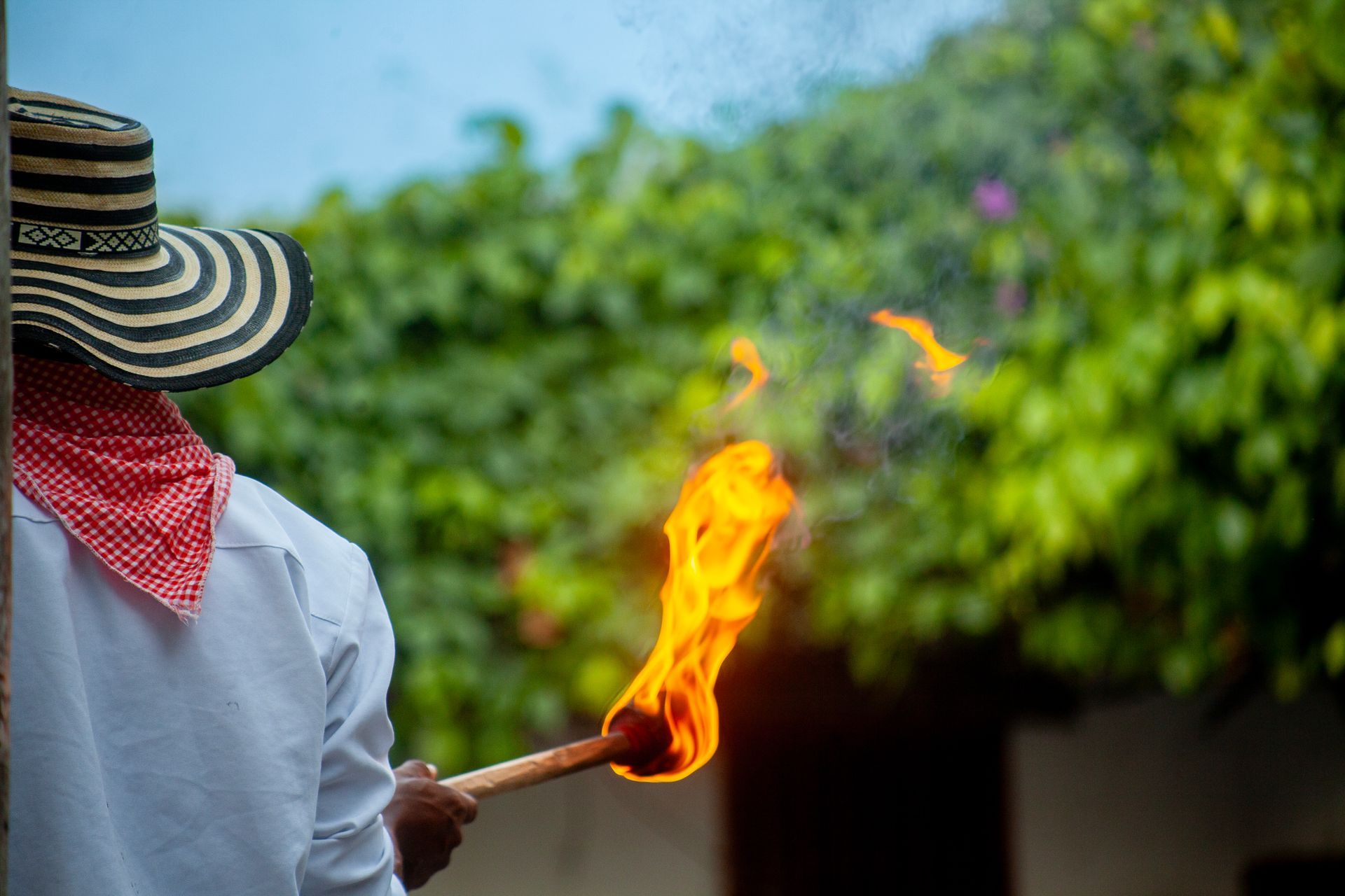 Un hombre con sombrero sostiene una antorcha en su mano.