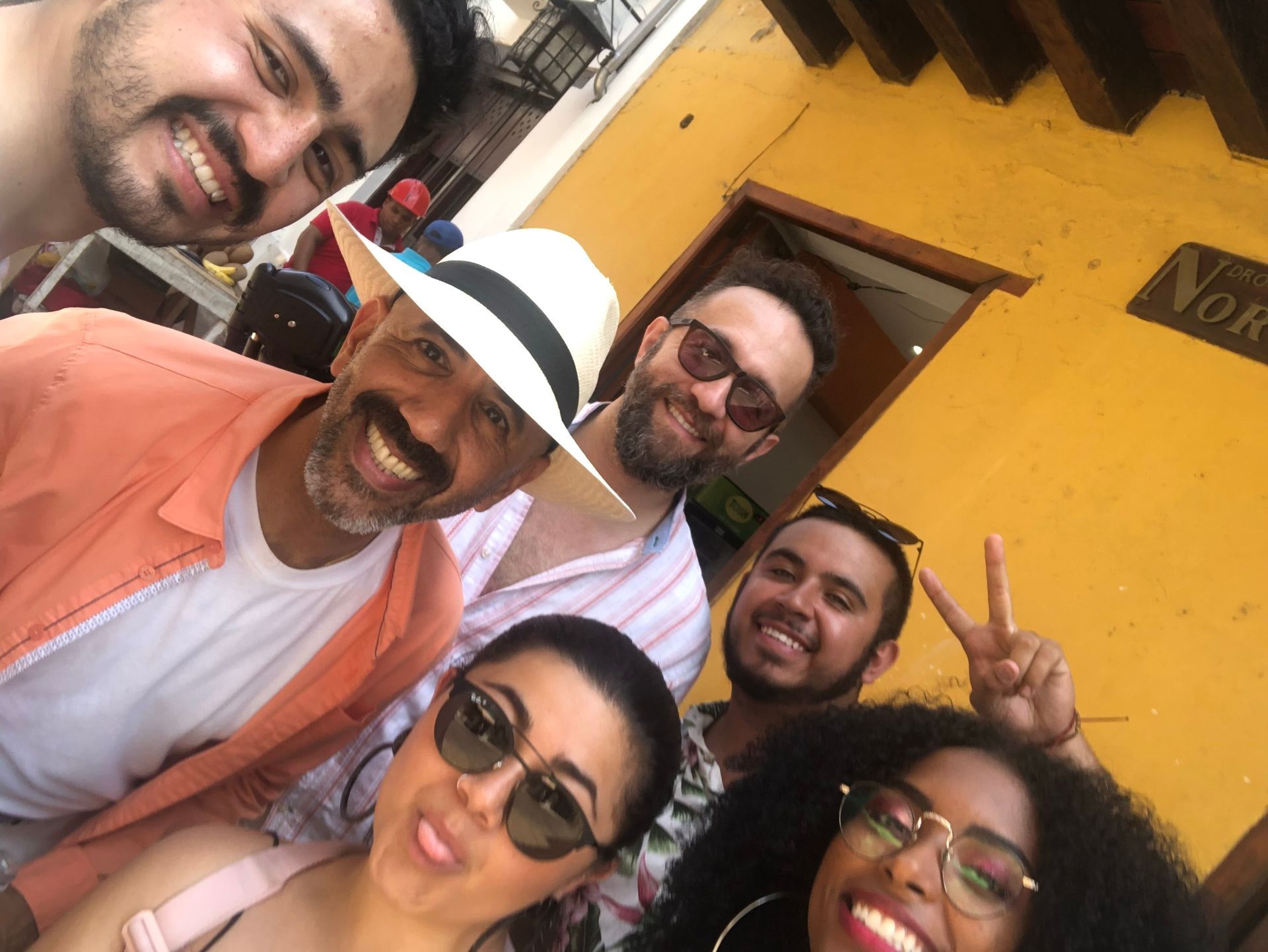 Un grupo de personas posan para una fotografía frente a un edificio amarillo.