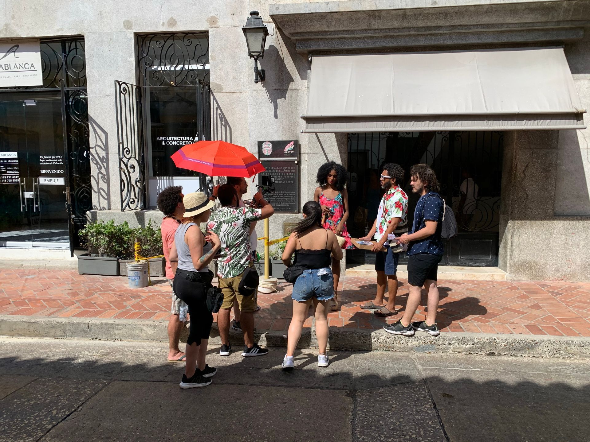 Un grupo de personas está de pie en la acera frente a un edificio.
