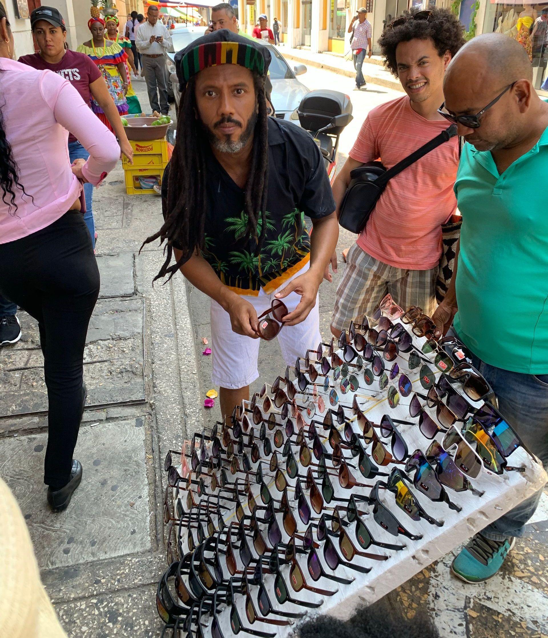 Un grupo de personas están de pie alrededor de una mesa llena de gafas de sol.