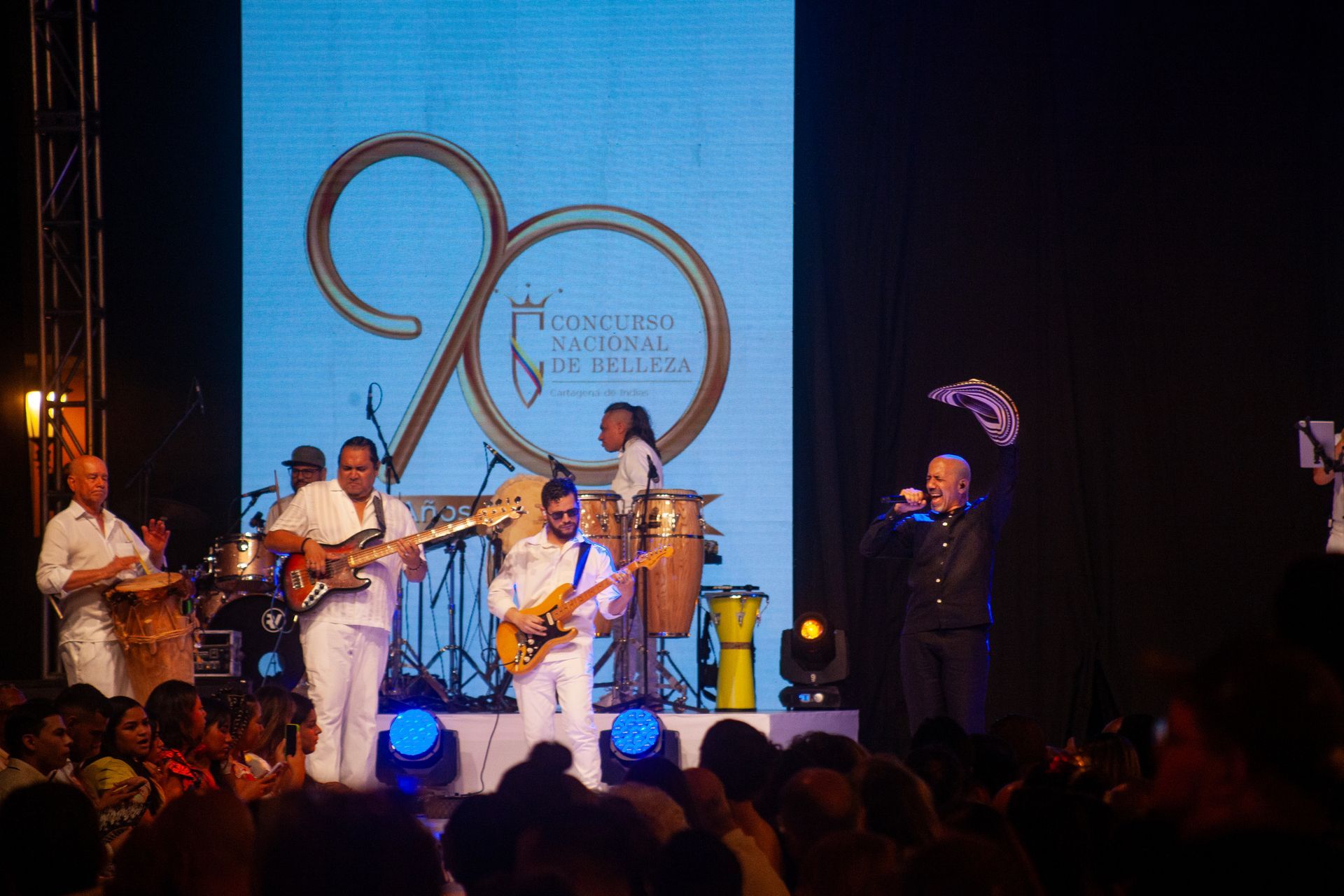 Un grupo de personas toca instrumentos en un escenario frente a una multitud.