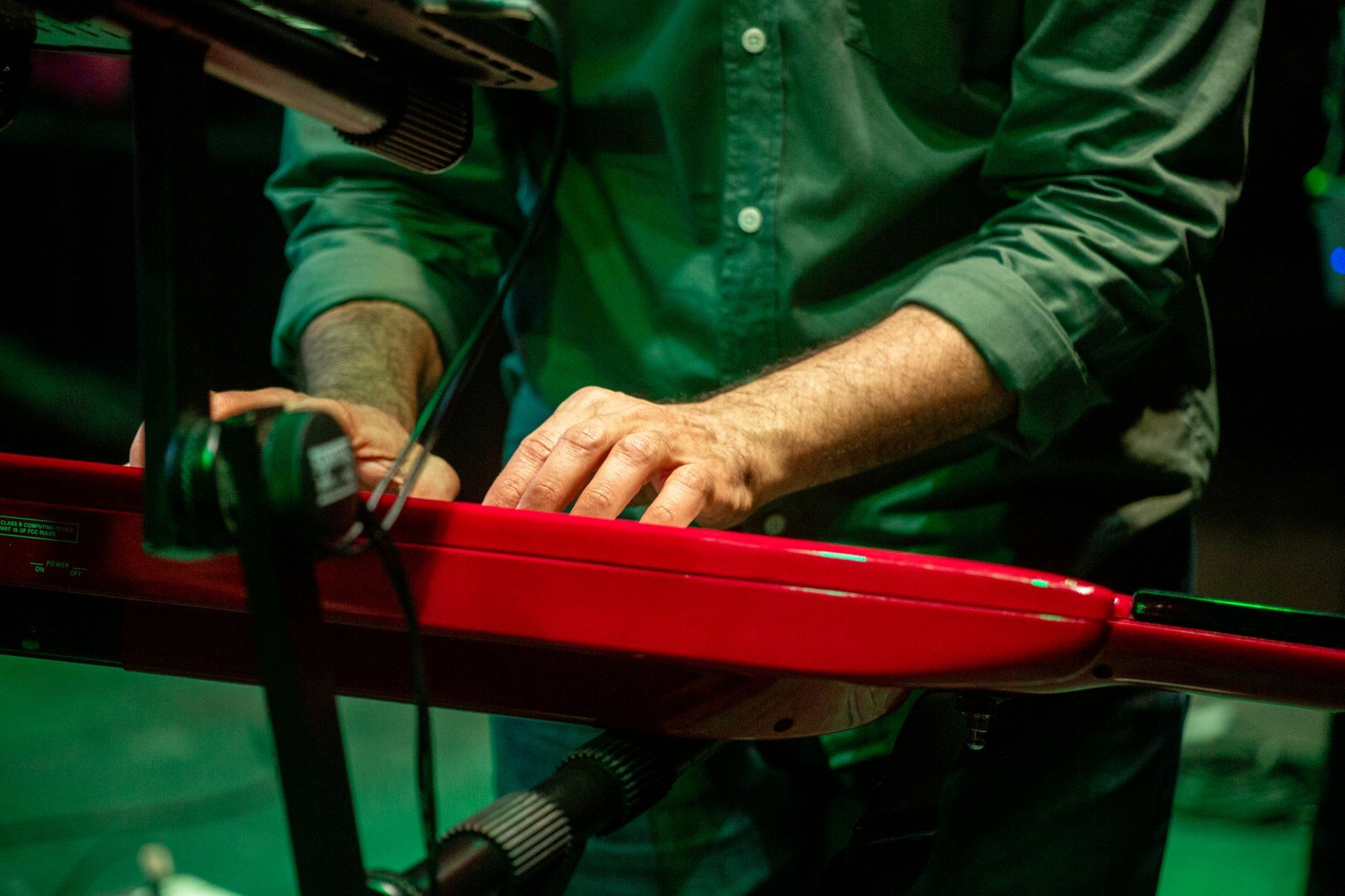 Un hombre con una camisa verde está tocando un teclado rojo.