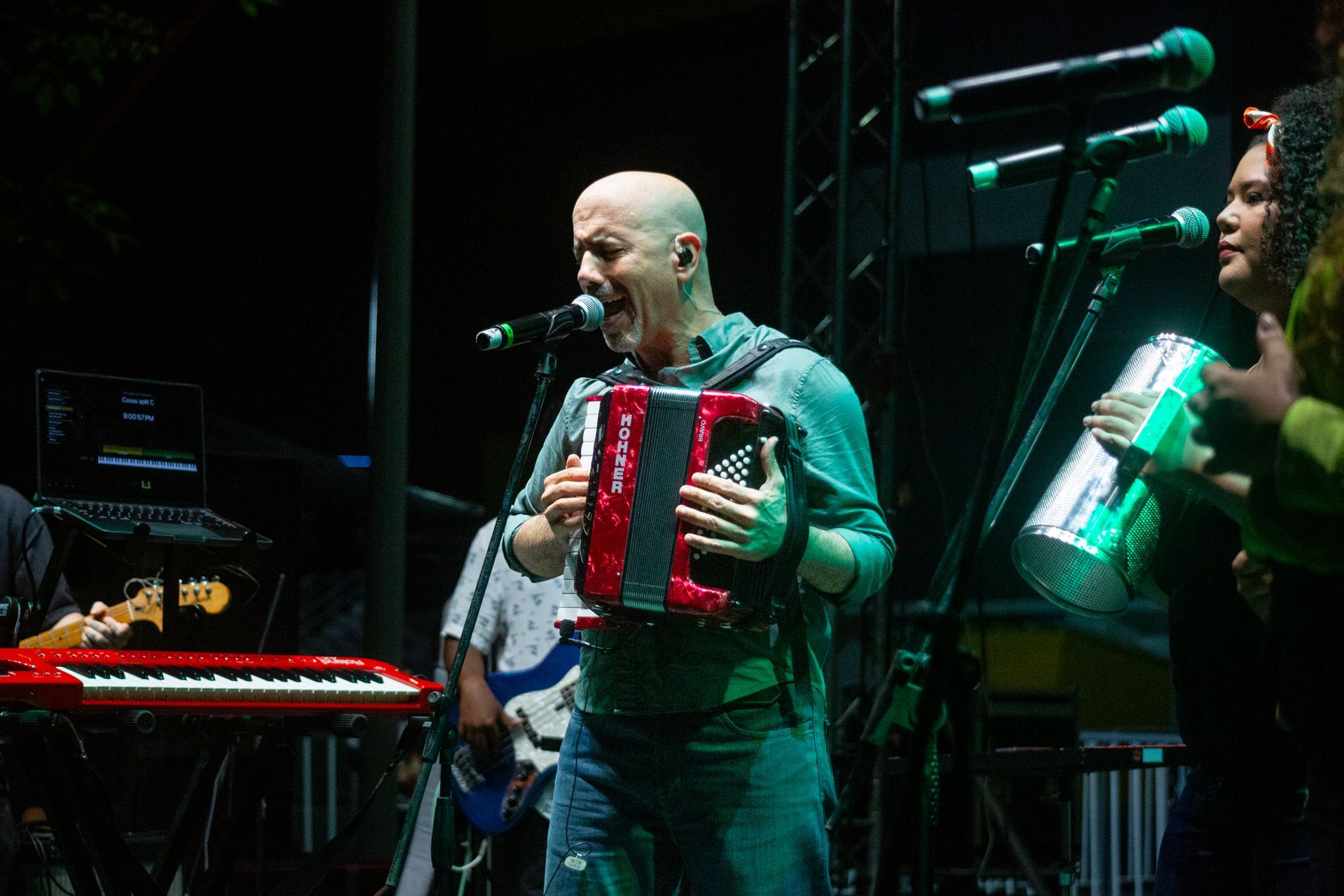 Un hombre toca el acordeón y canta en un micrófono en un escenario.