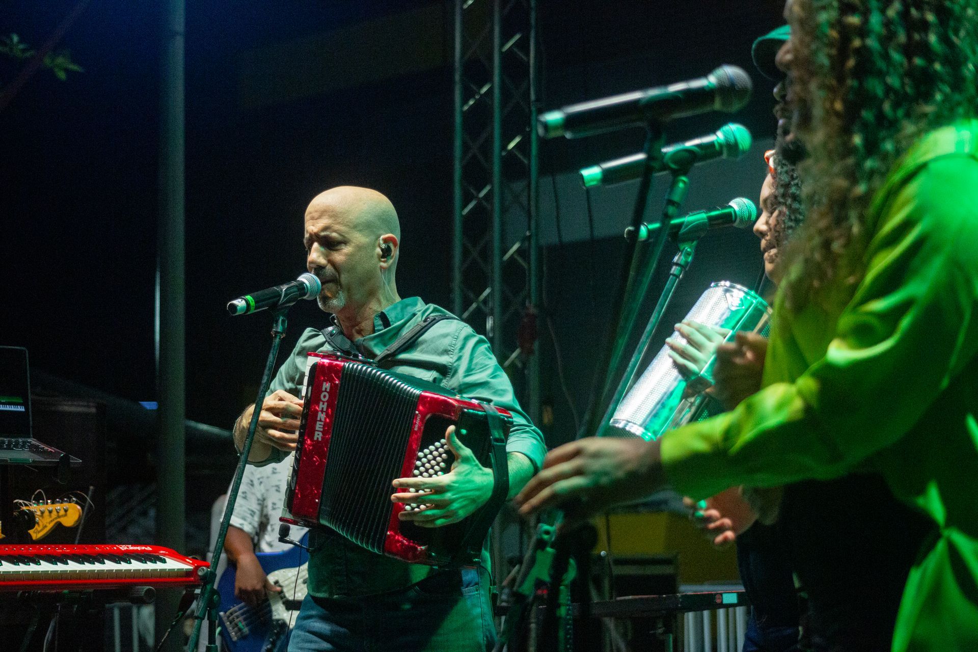 Un hombre toca el acordeón y canta en un micrófono en un escenario.