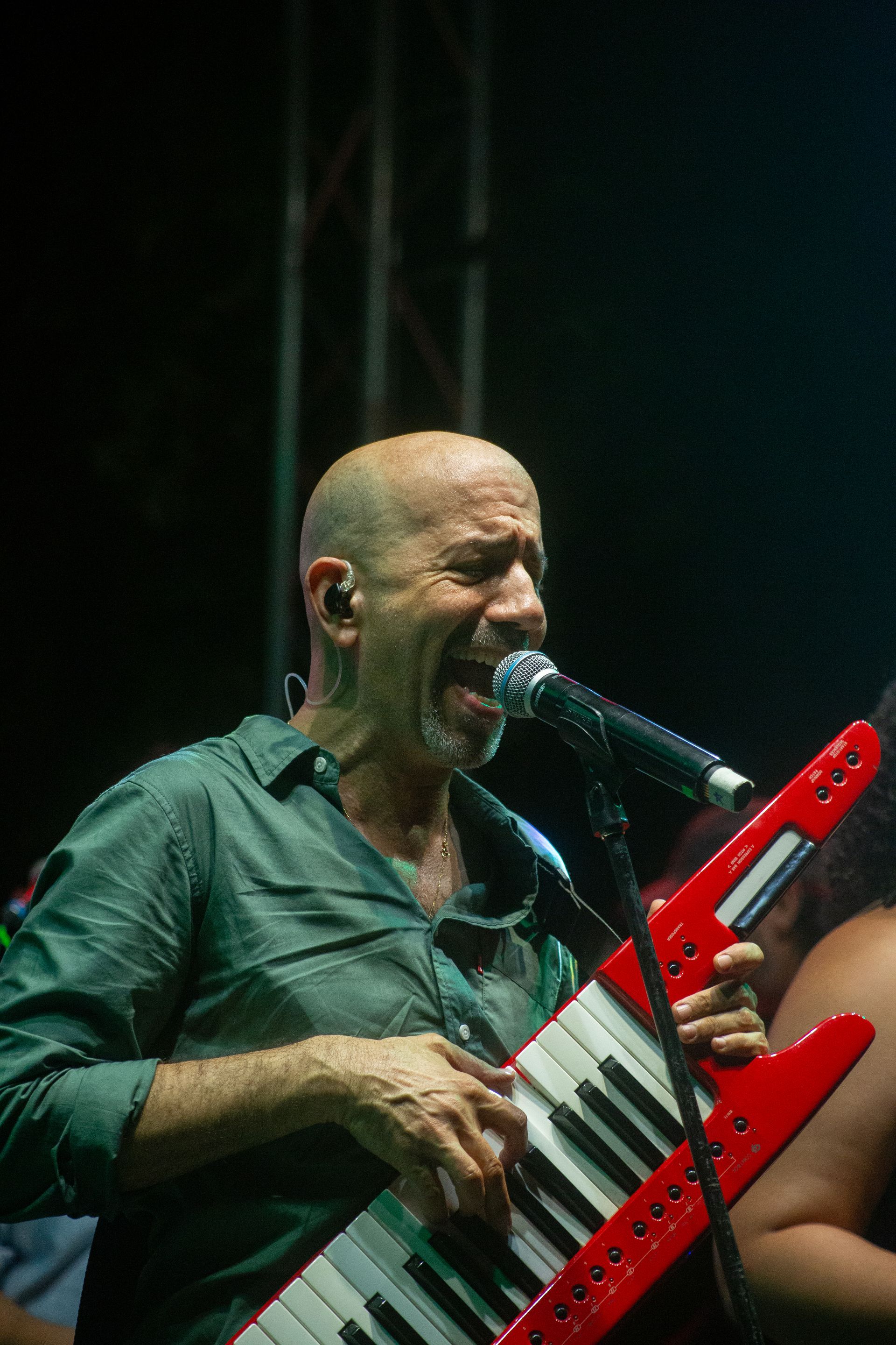 Un hombre canta en un micrófono mientras sostiene un teclado rojo.