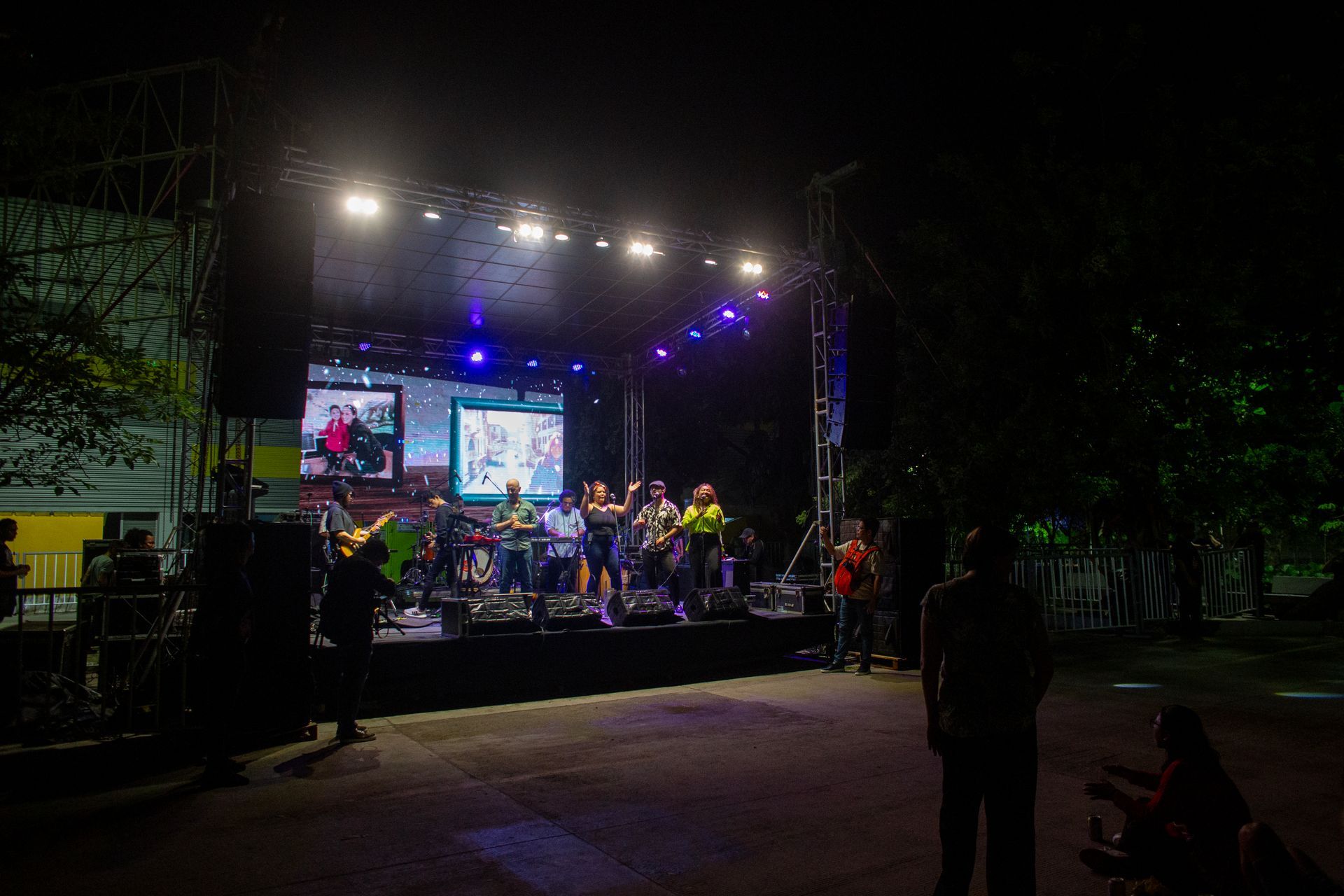 Un grupo de personas se encuentra frente a un escenario por la noche.